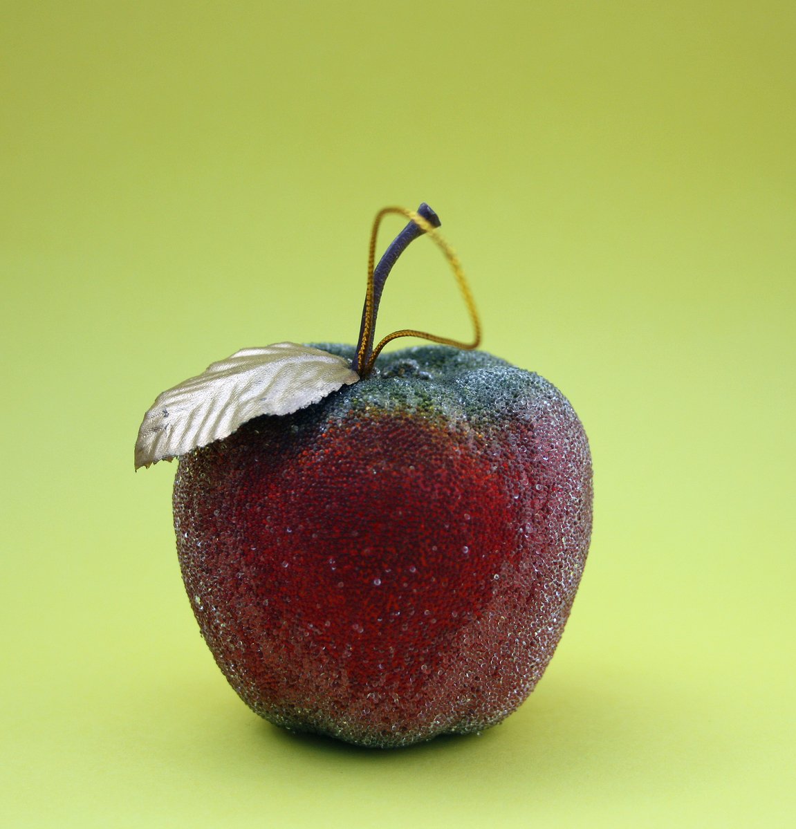 an apple with a leaf and some light brown, red and green on top