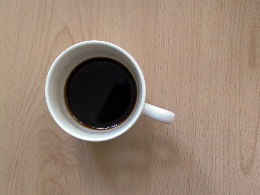the cup of coffee is placed on a wooden surface