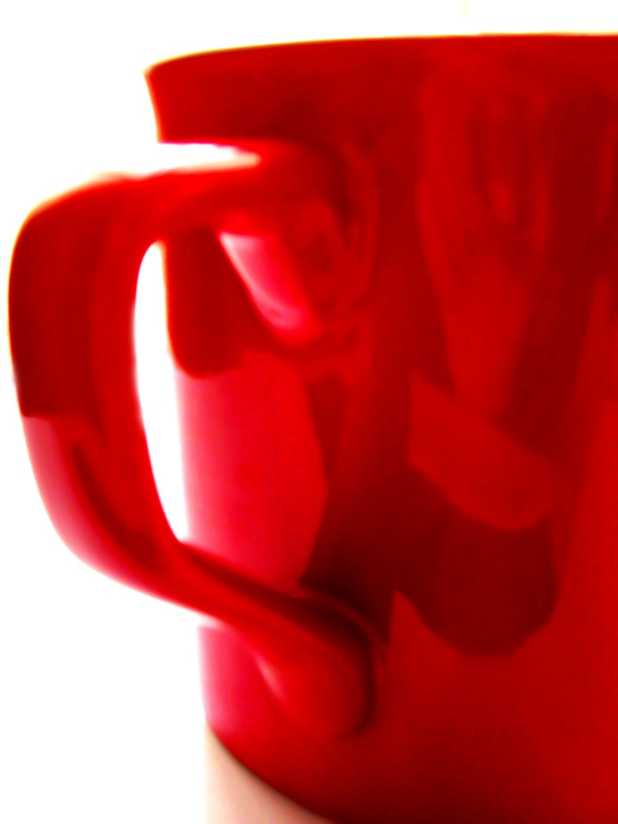 a red mug is on a white table