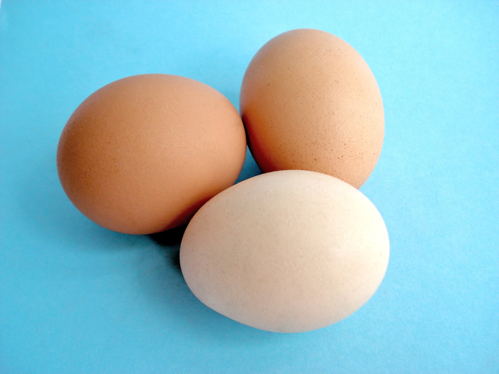 three eggs that are sitting on a blue surface
