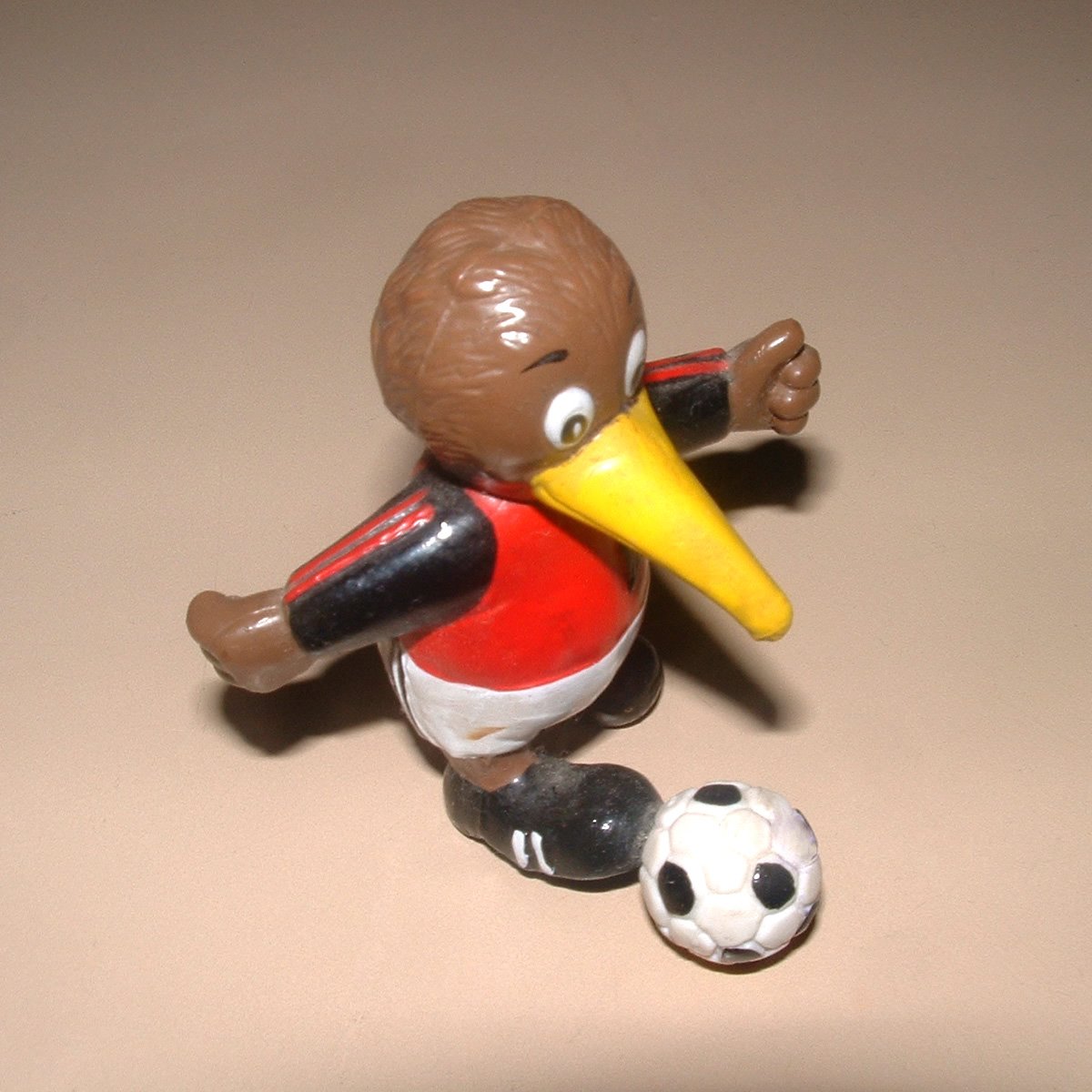 a toy figure holds a plastic football and has a yellow yellow beak