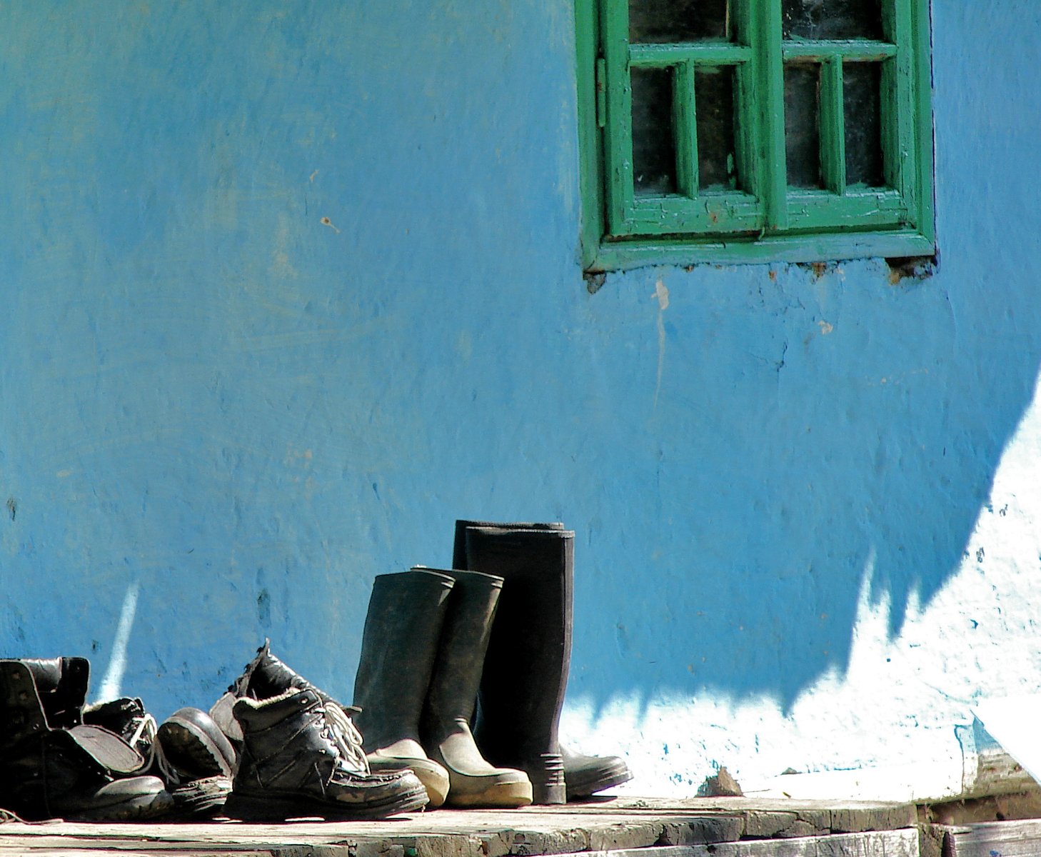 shoes stacked up against a blue wall near a window