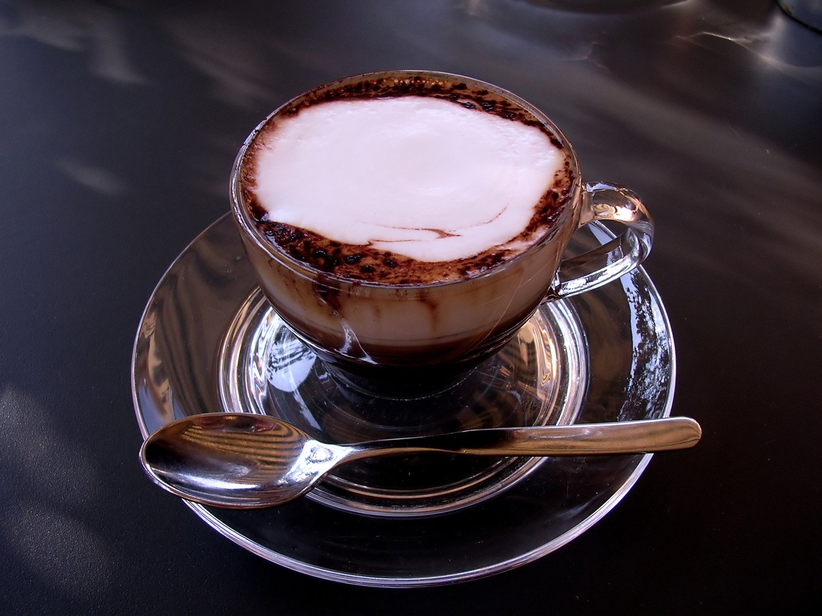 a cup of  chocolate sits on a saucer with a spoon