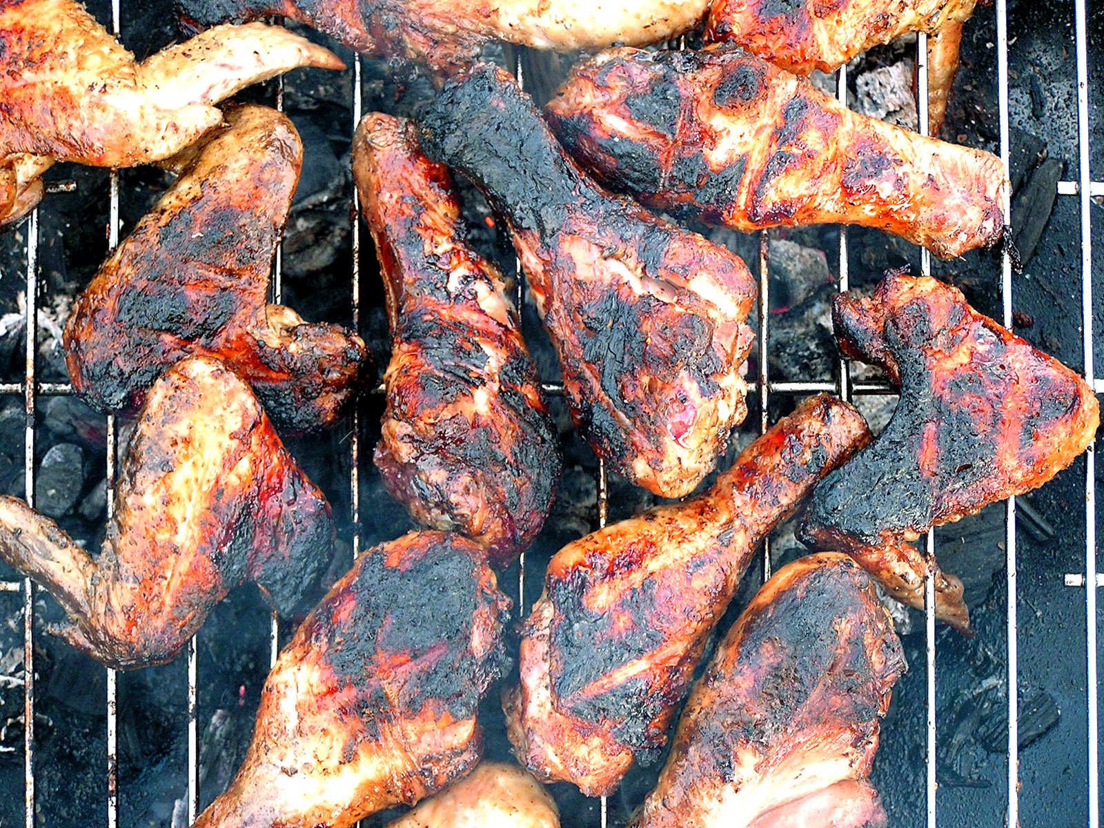 several pork legs cooking on a bbq grill