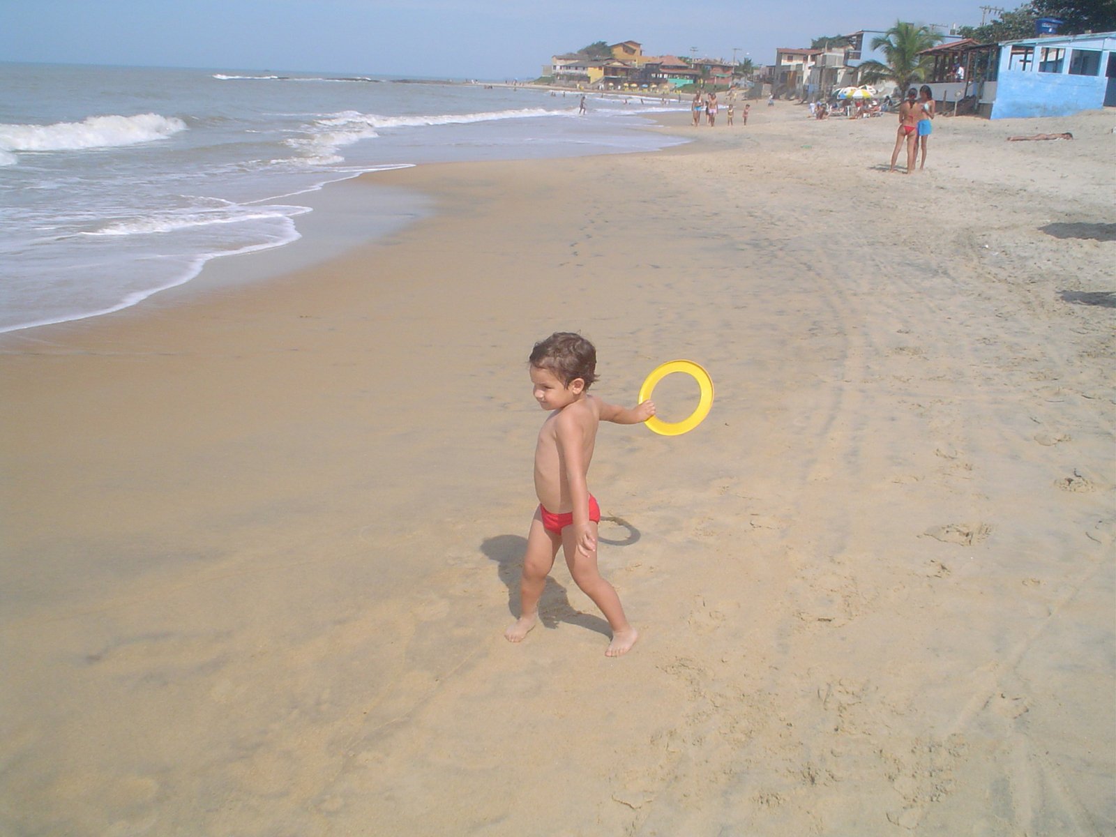 a little boy is holding a frisbee at the beach