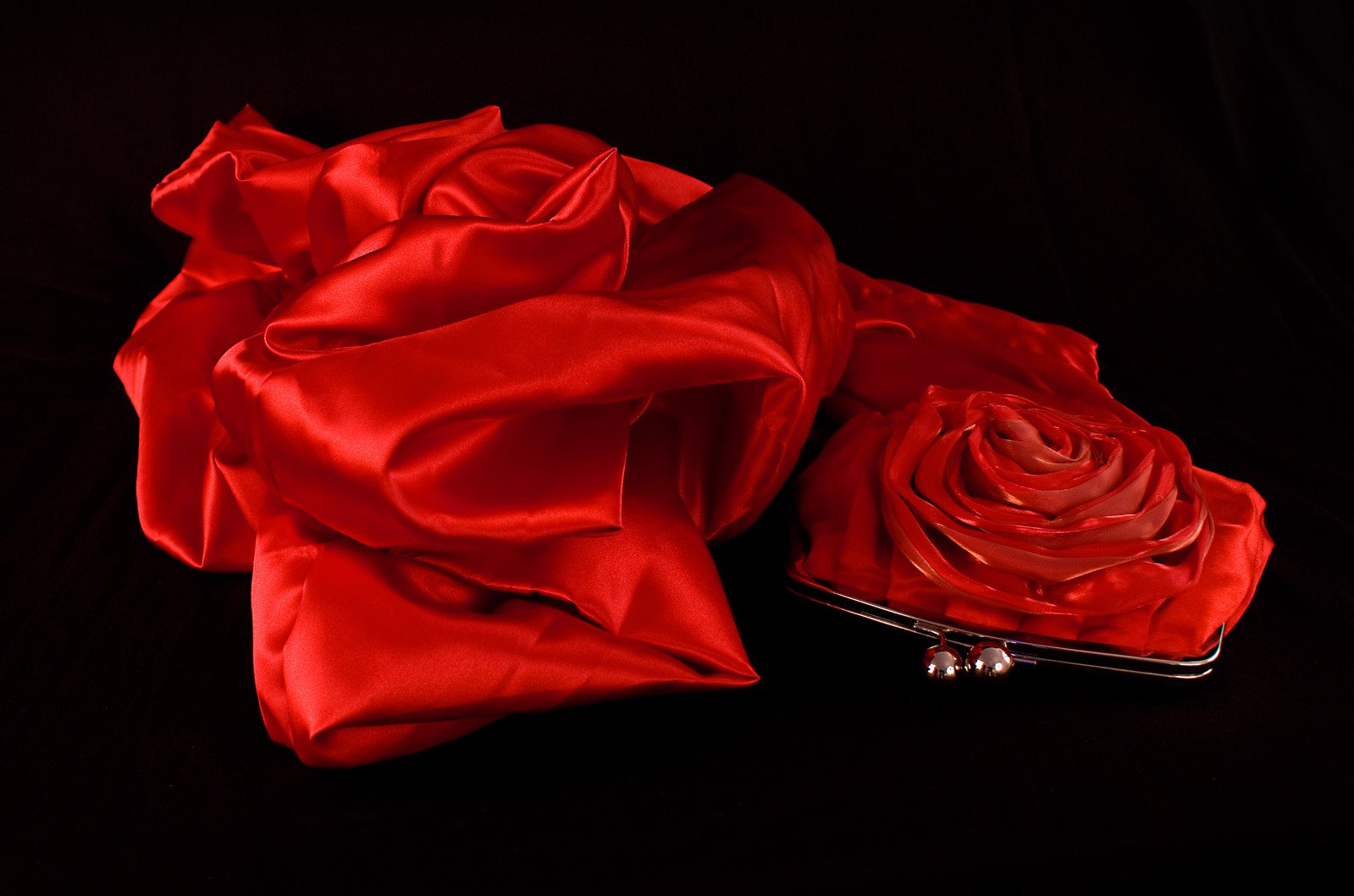 red satin fabric covering a flower on a black background