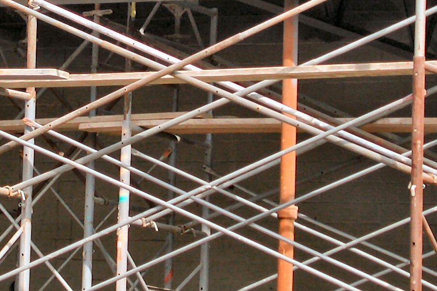 several birds sitting in metal scaffolding in a courtyard