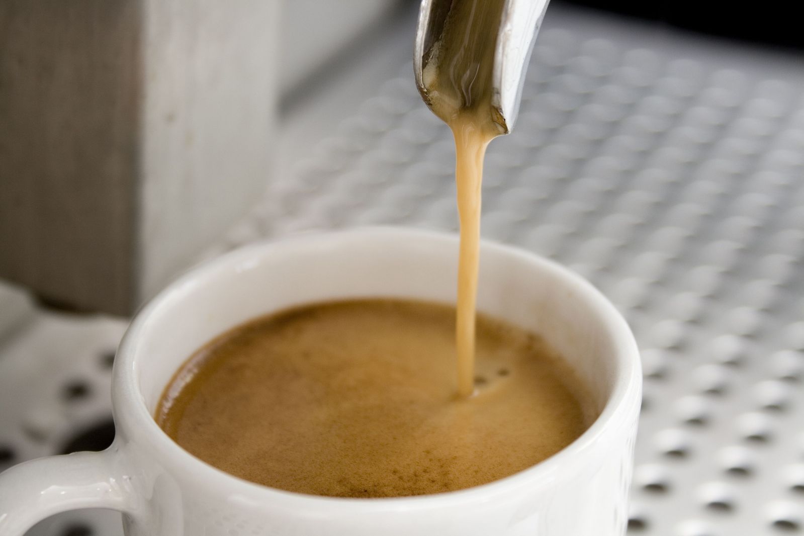 coffee pouring into a white cup with brown caramel