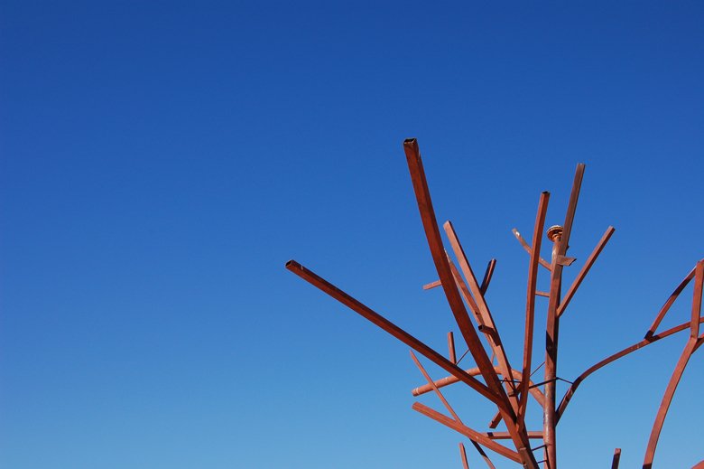 a metal sculpture in front of a blue sky