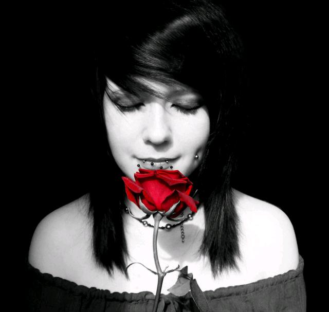 a woman holding a rose up to her face