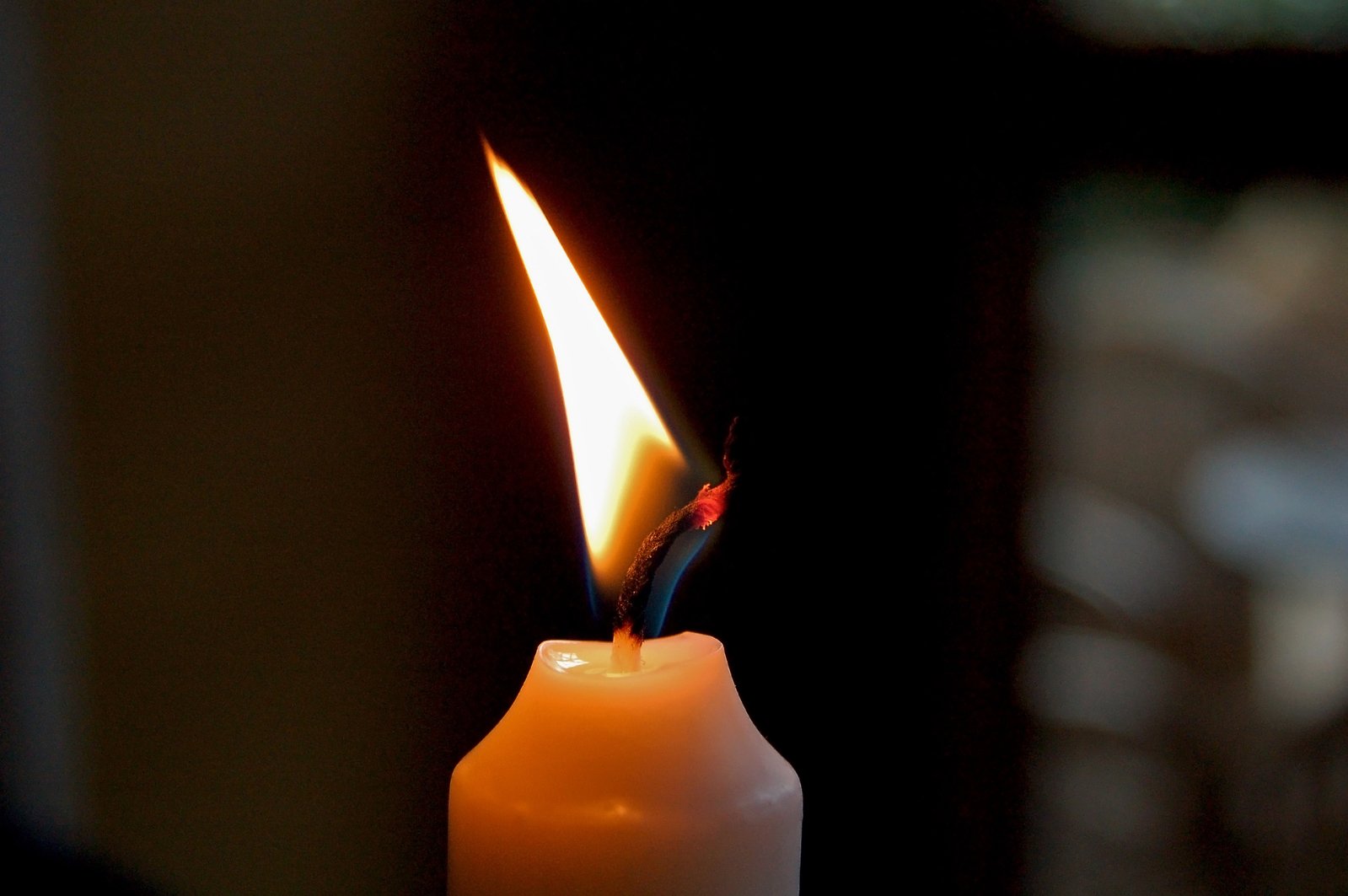 a candle with one glowing orange light with black background