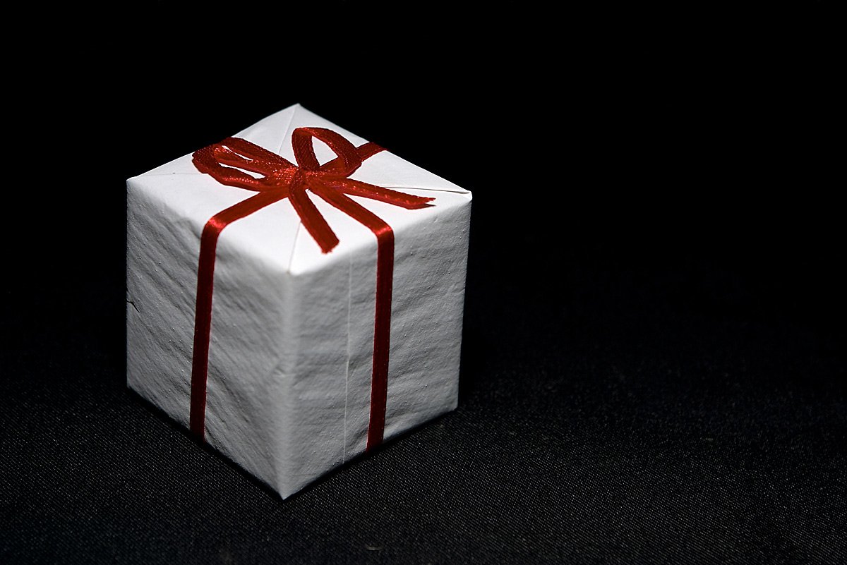 a white wrapped gift with a red ribbon