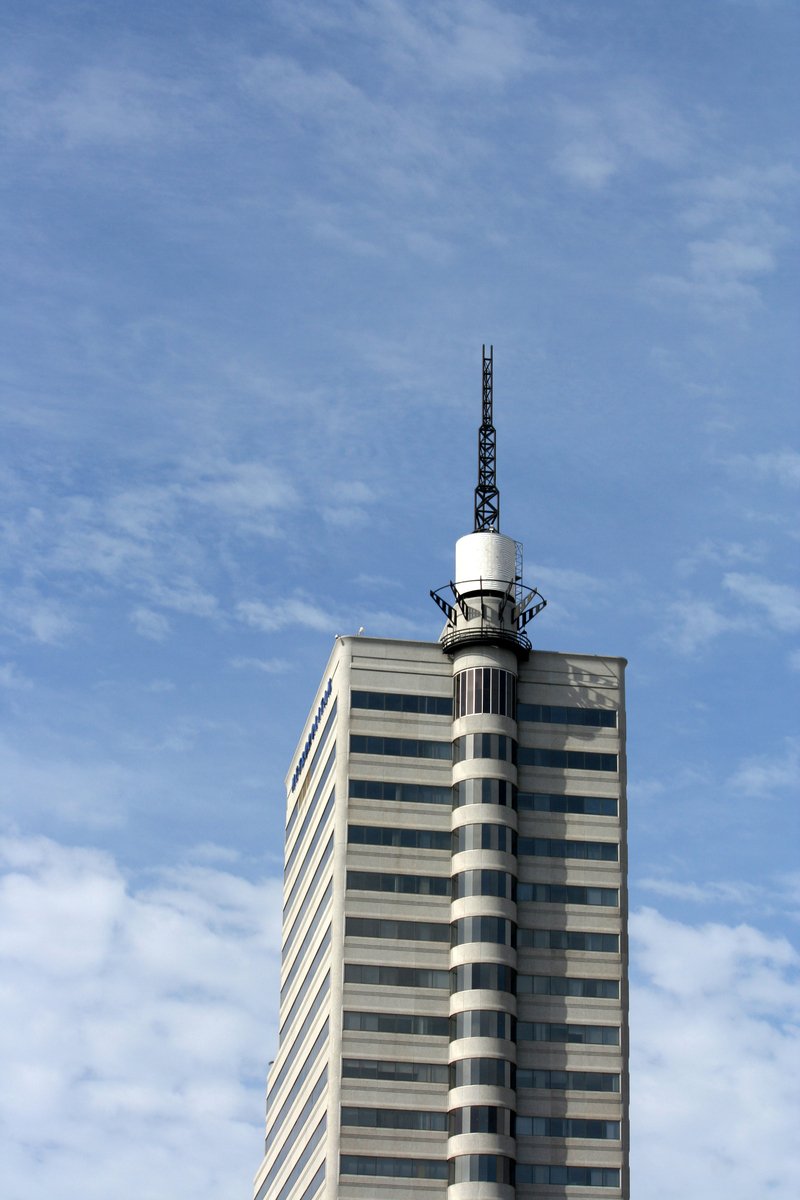 a tall building with a tower top and a satellite antenna