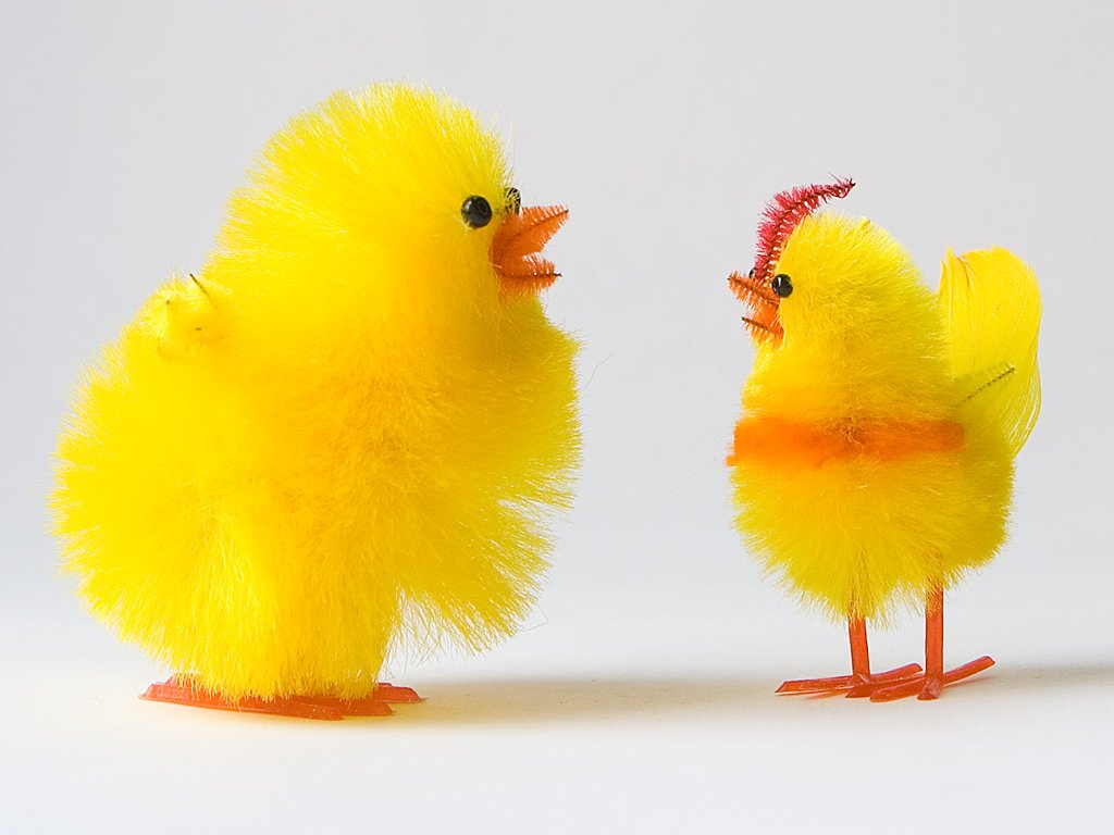 a small yellow toy chicken standing next to a smaller one