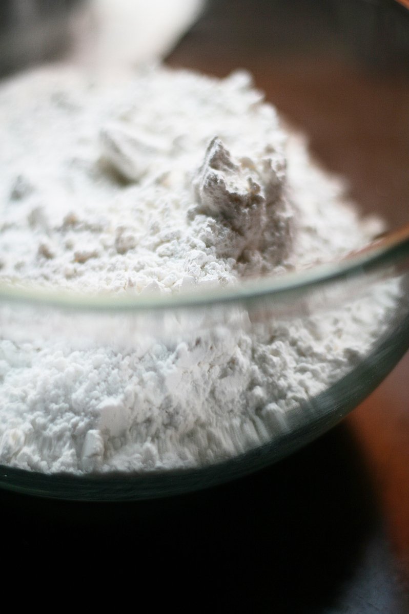 a bowl of white flour sits on the table