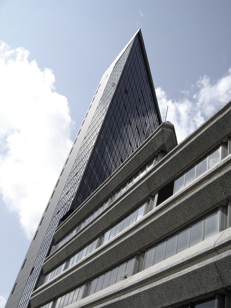a large grey building with a massive skyscr