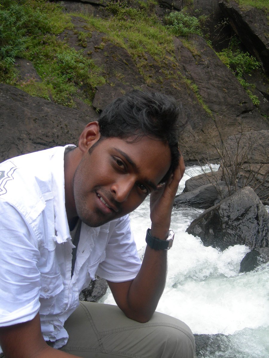 a man sitting on rocks next to water