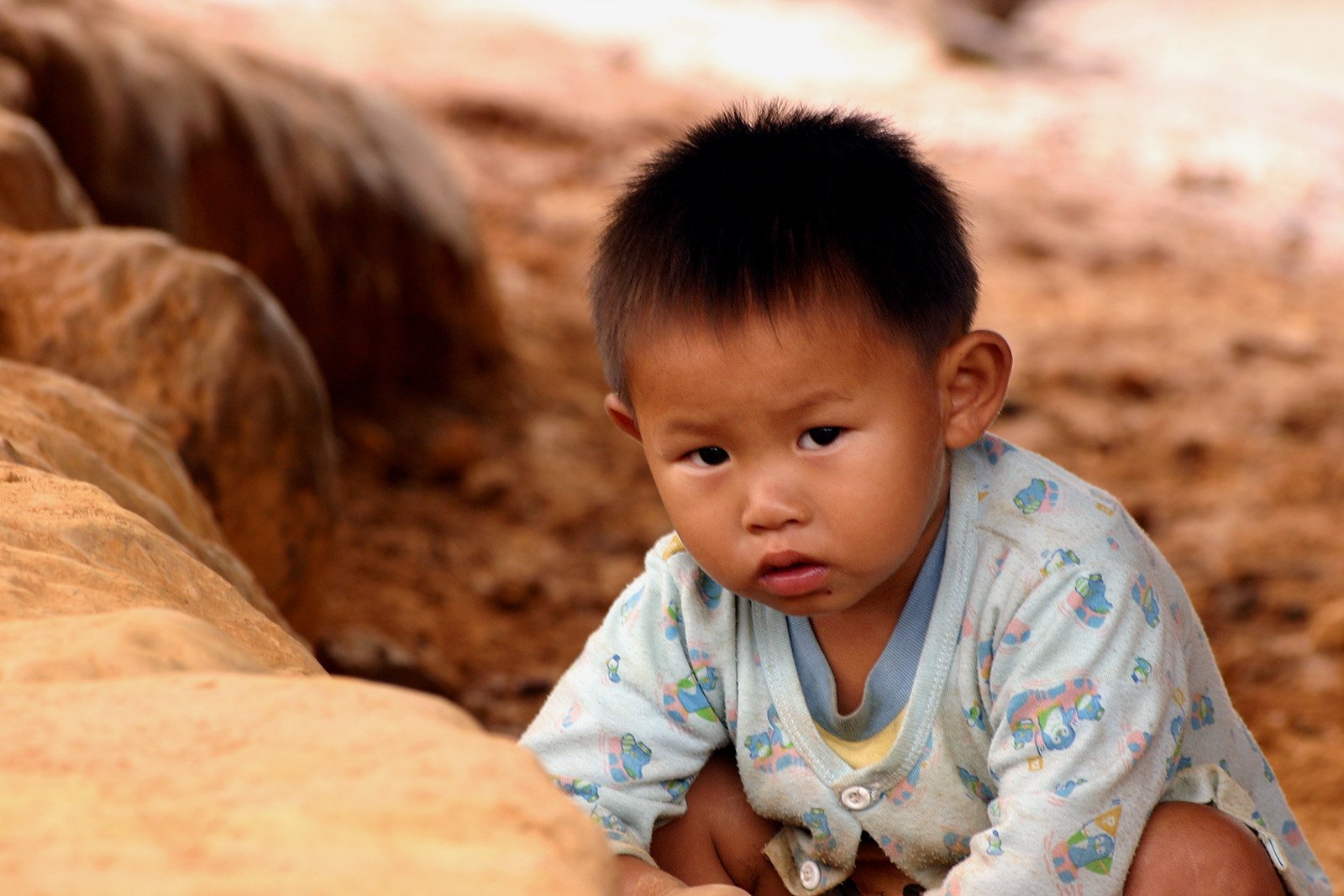 a baby sitting on top of a large rock