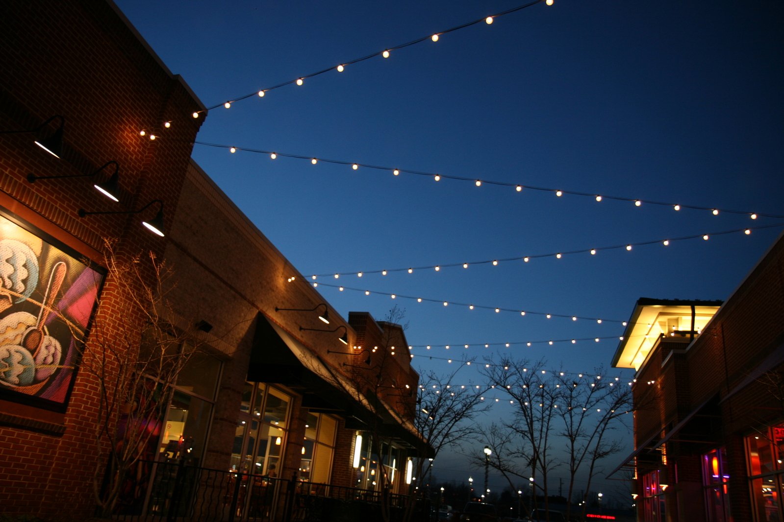 a street at night with many lights hanging on buildings