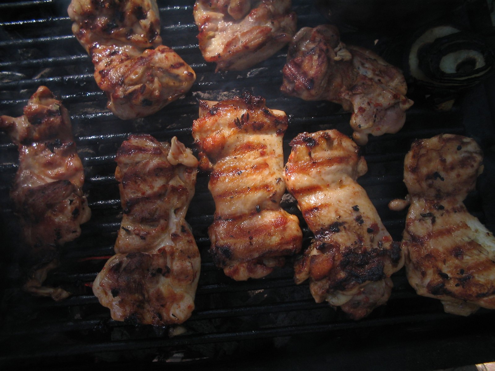 a bbq with chicken and other food being prepared on a grill