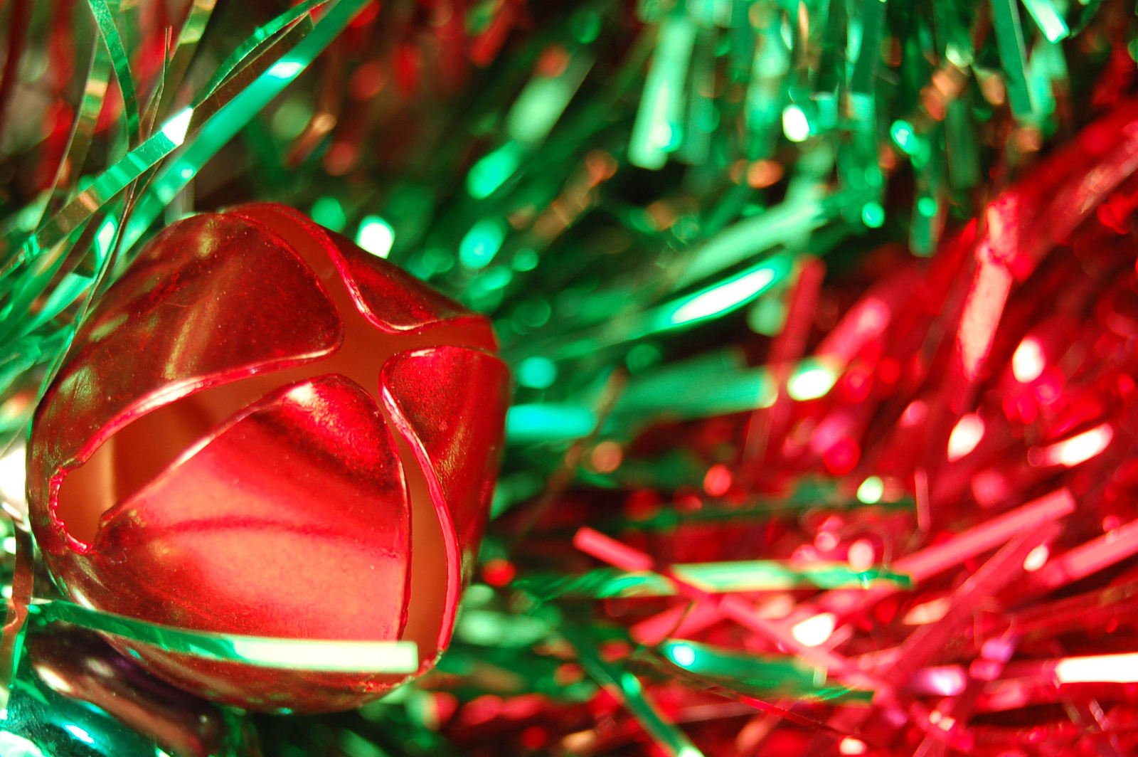 a red ornament sitting on a green and pink christmas tree