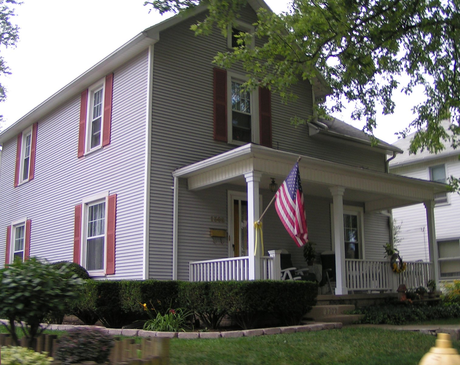 an american flag on the corner of a two story house