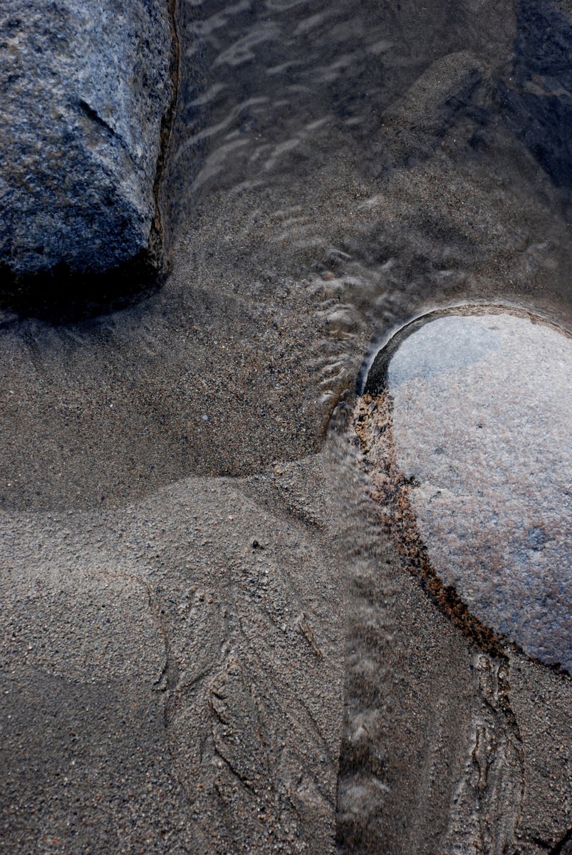 there is a rock in the sand with water on it