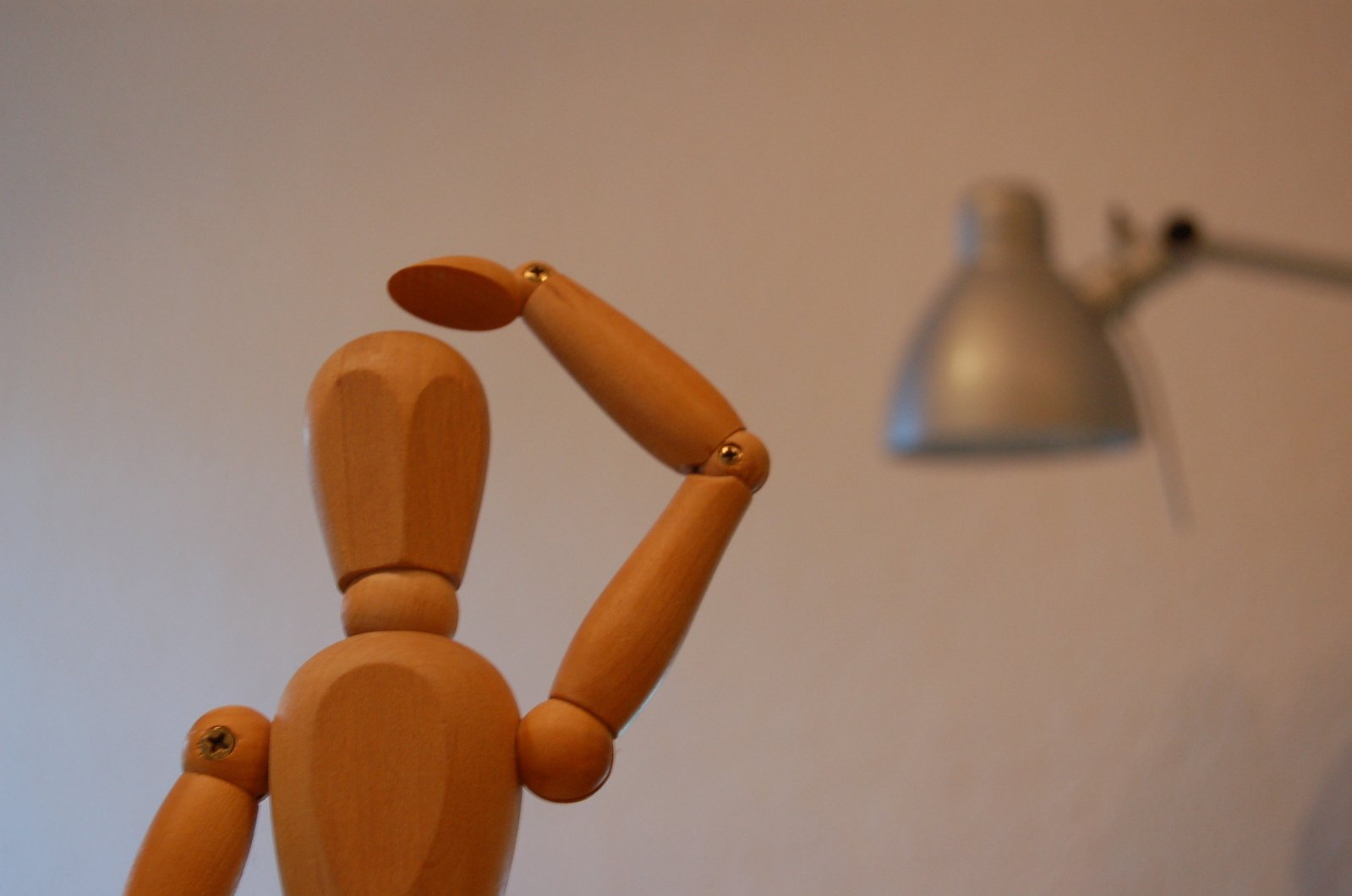 the wooden man has two arms up in an office setting
