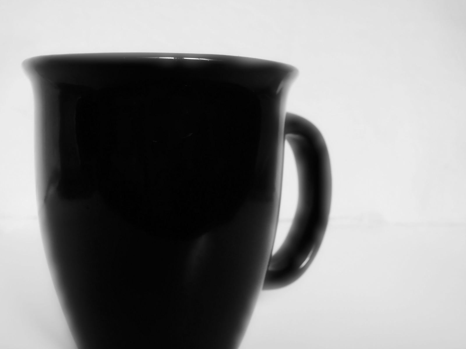 a black coffee mug is sitting on a white table