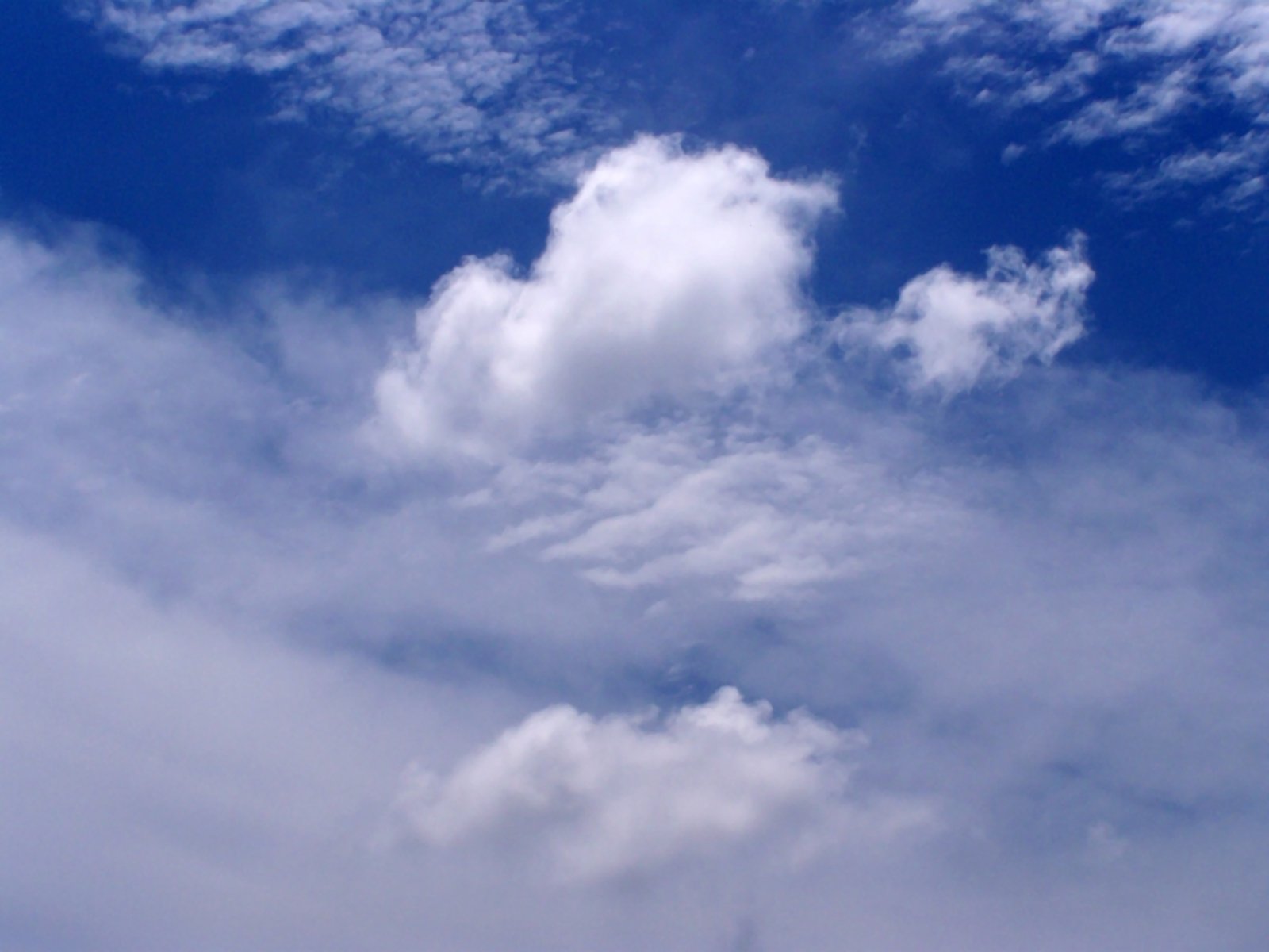 a jet flying through a very cloudy blue sky