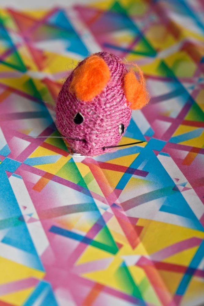 a knitted mouse is shown on colorful papers