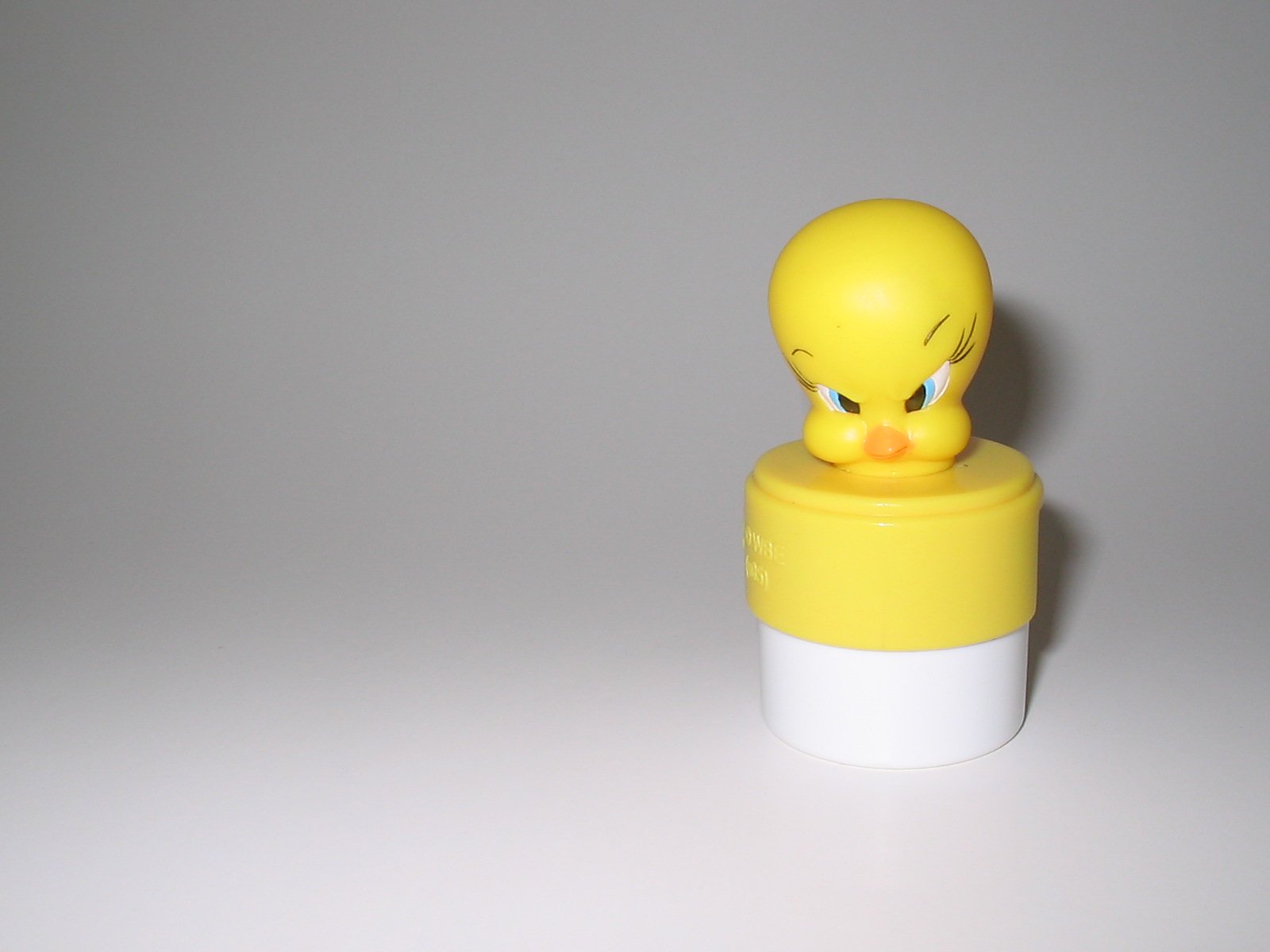 a rubber ducky yellow with big eyes on a white container