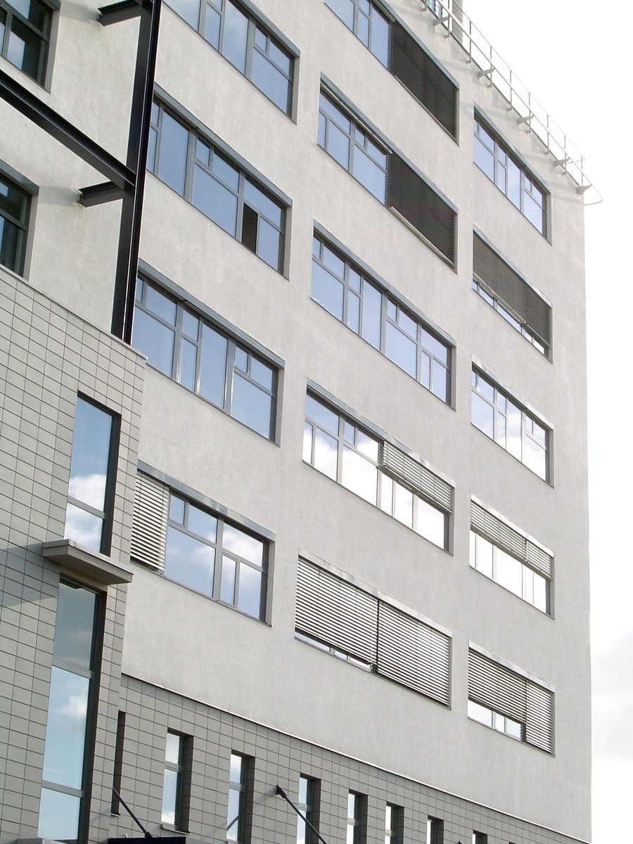 a gray building has several windows with a few bars on top