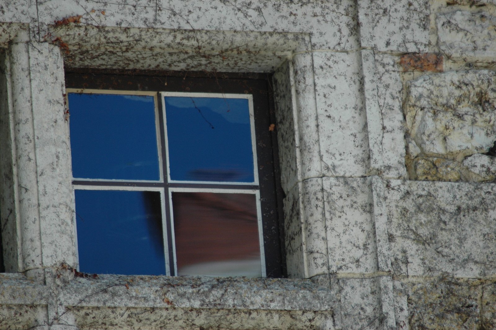 a broken window with blue paint and a sky background