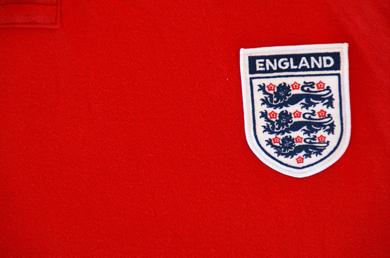 the england crest is on the red shirt