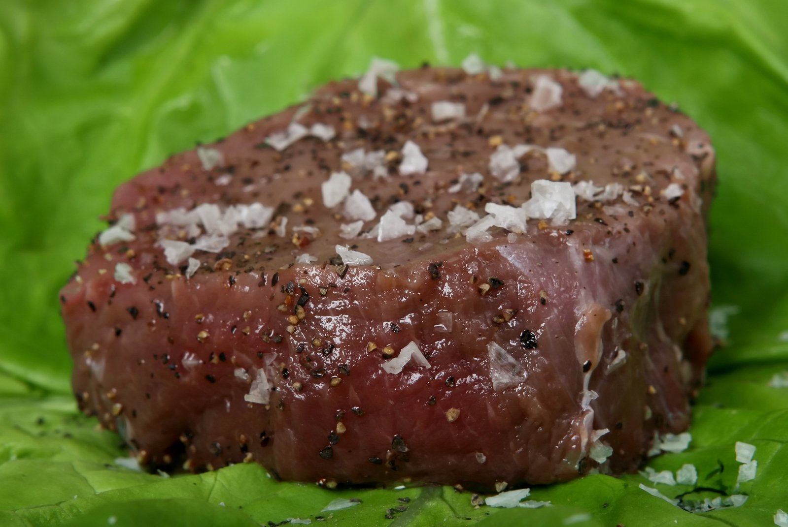 a piece of steak sitting on top of green leaves