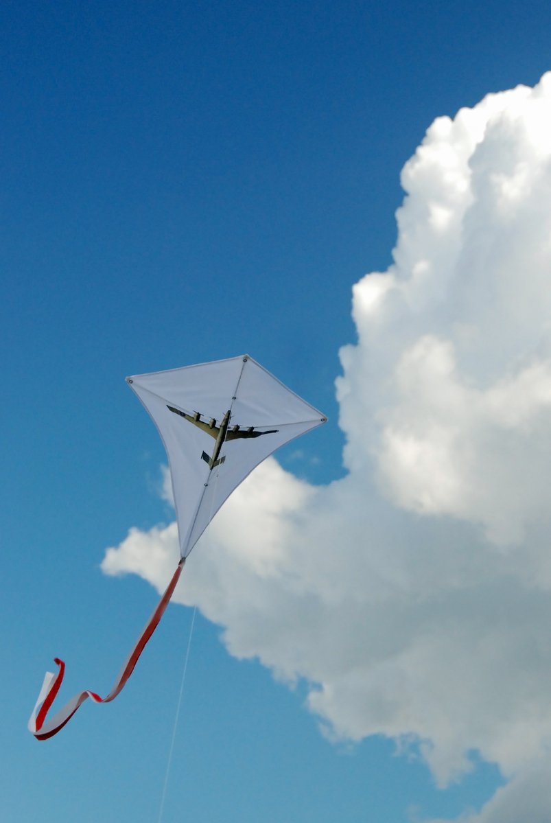 a white kite flying through a cloudy sky