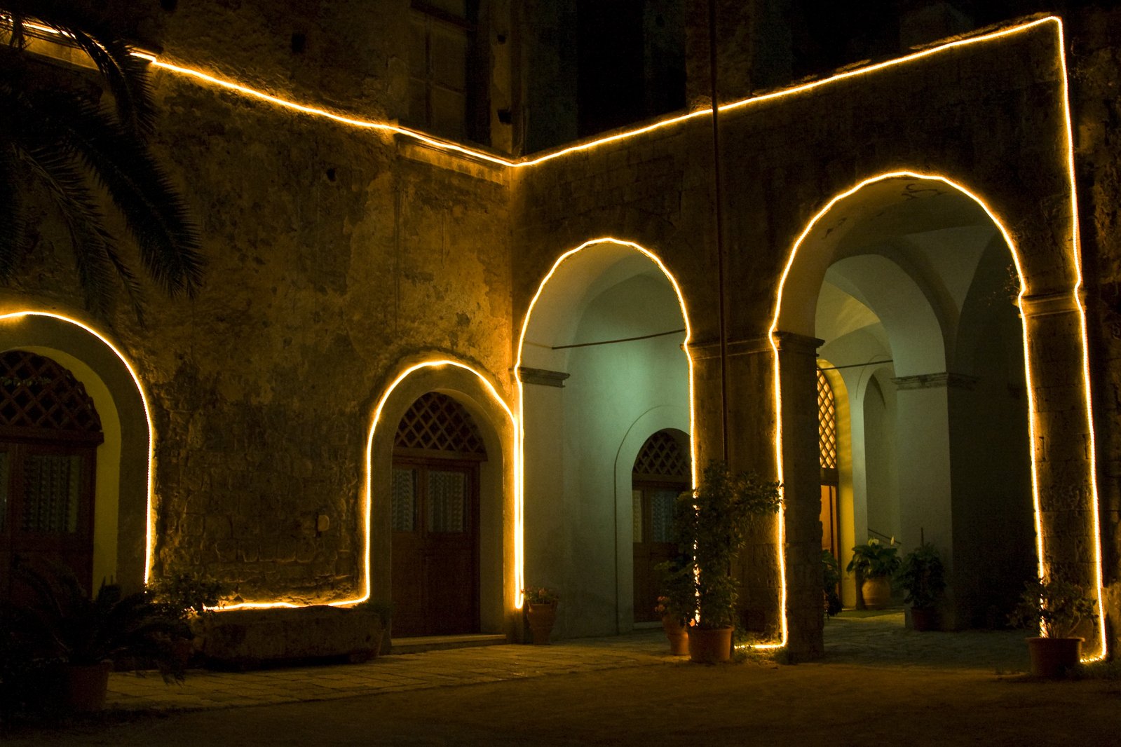 an archway with arches with bright lights and some palm trees