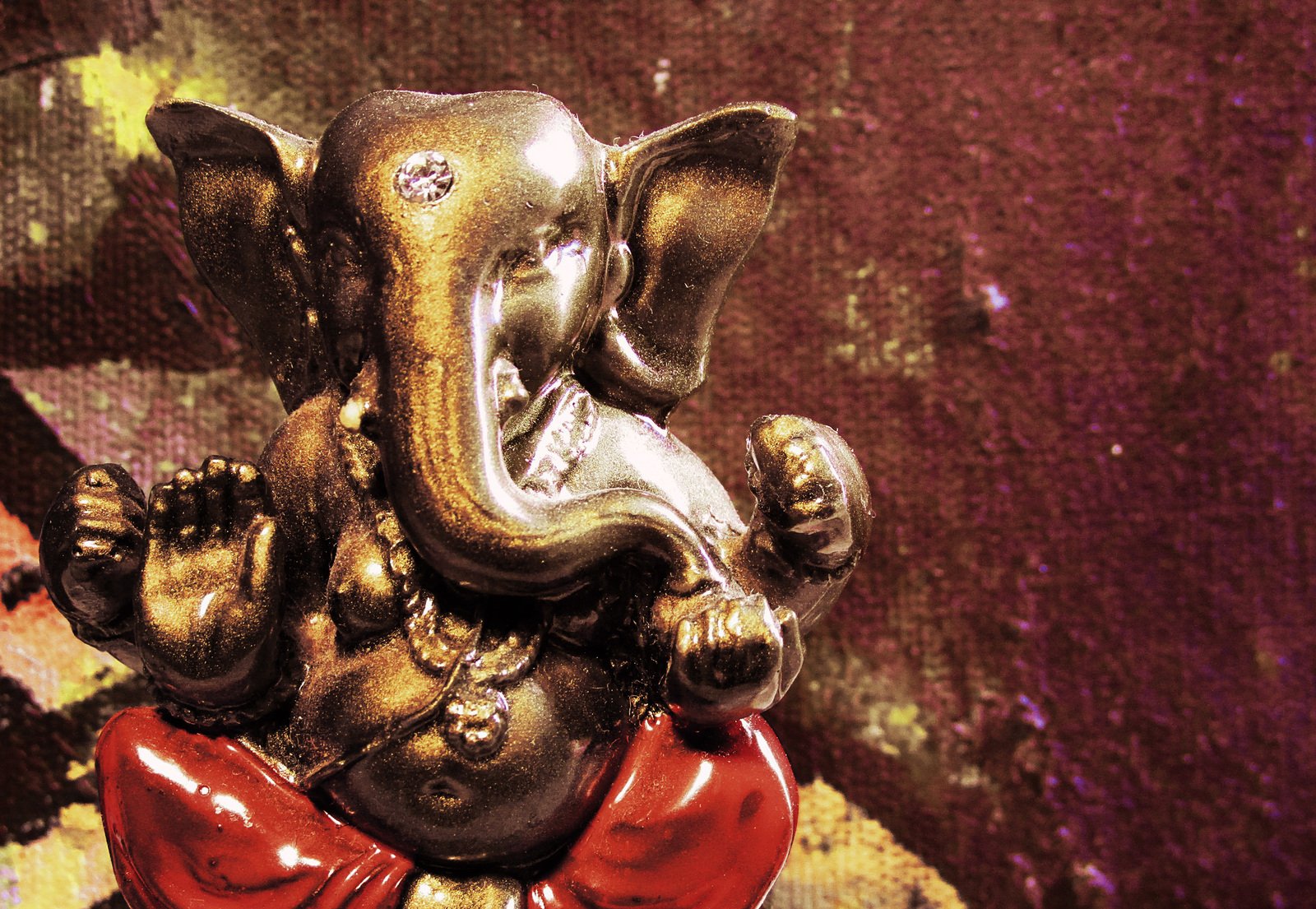 an old statue of a seated little elephant with a red bow tie