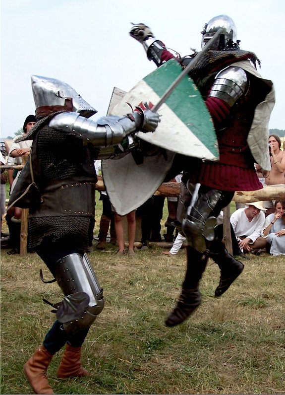 two knights wearing helmets, one holding a shield