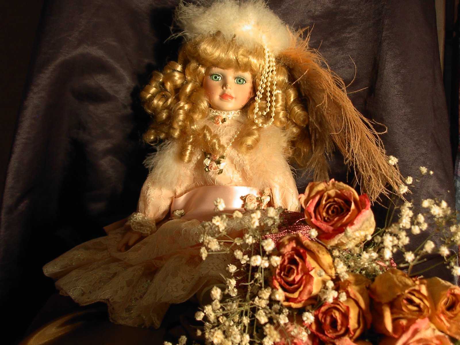 a close up of a doll next to a flower arrangement