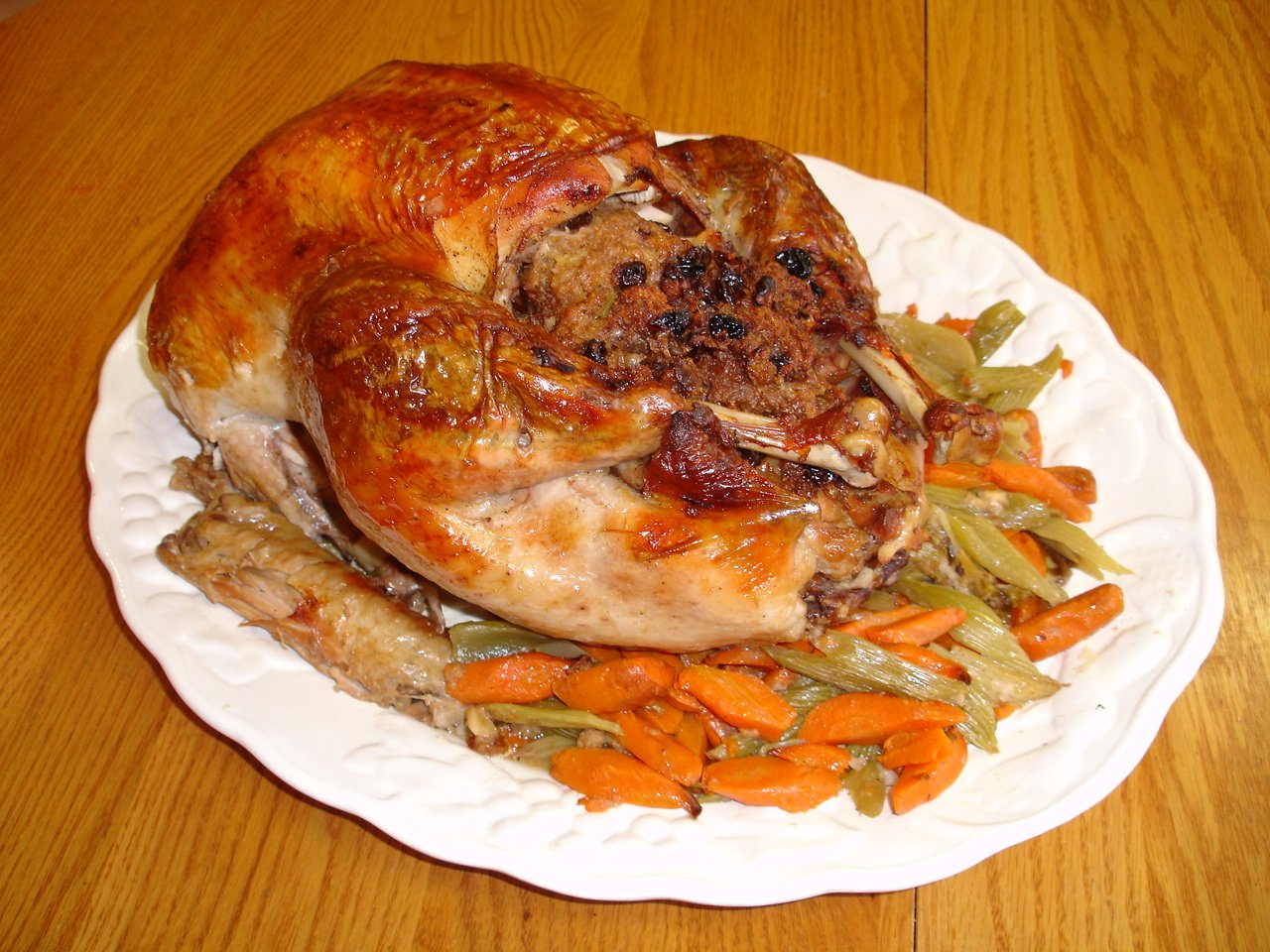 a large roast turkey sits on a white plate with some veggies and carrots