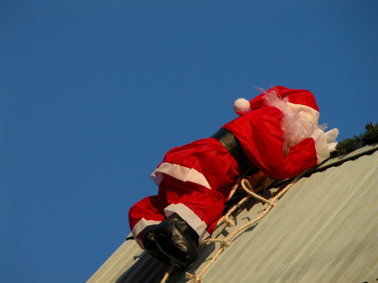 santa claus is climbing down from a roof