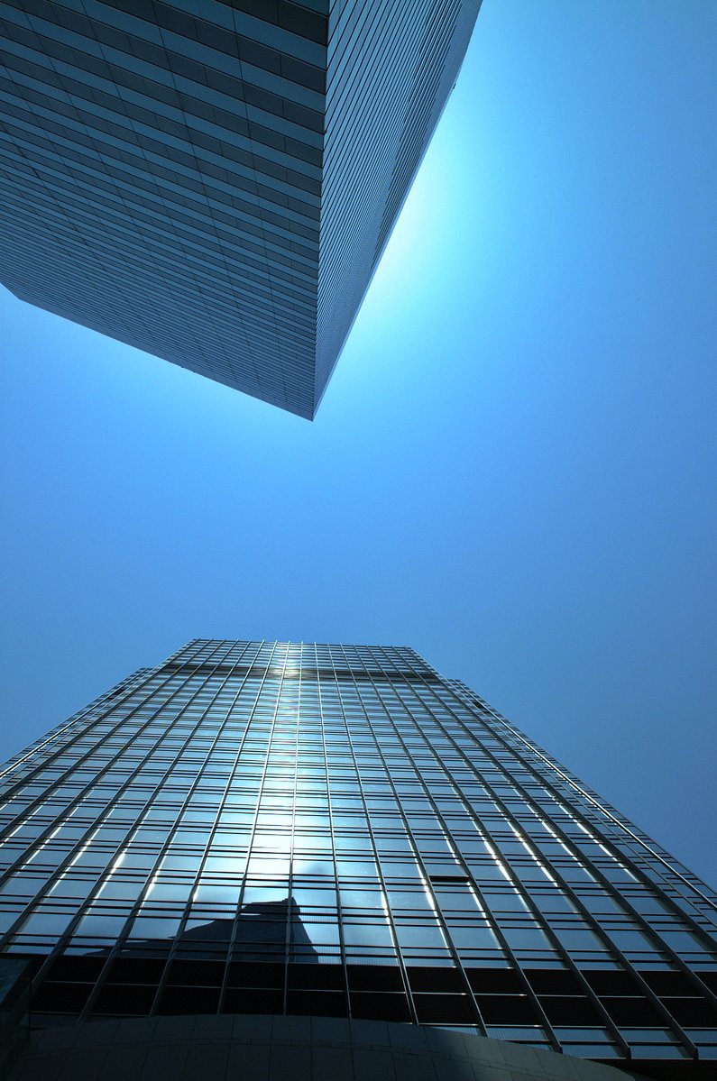 looking up at a high rise building against a blue sky