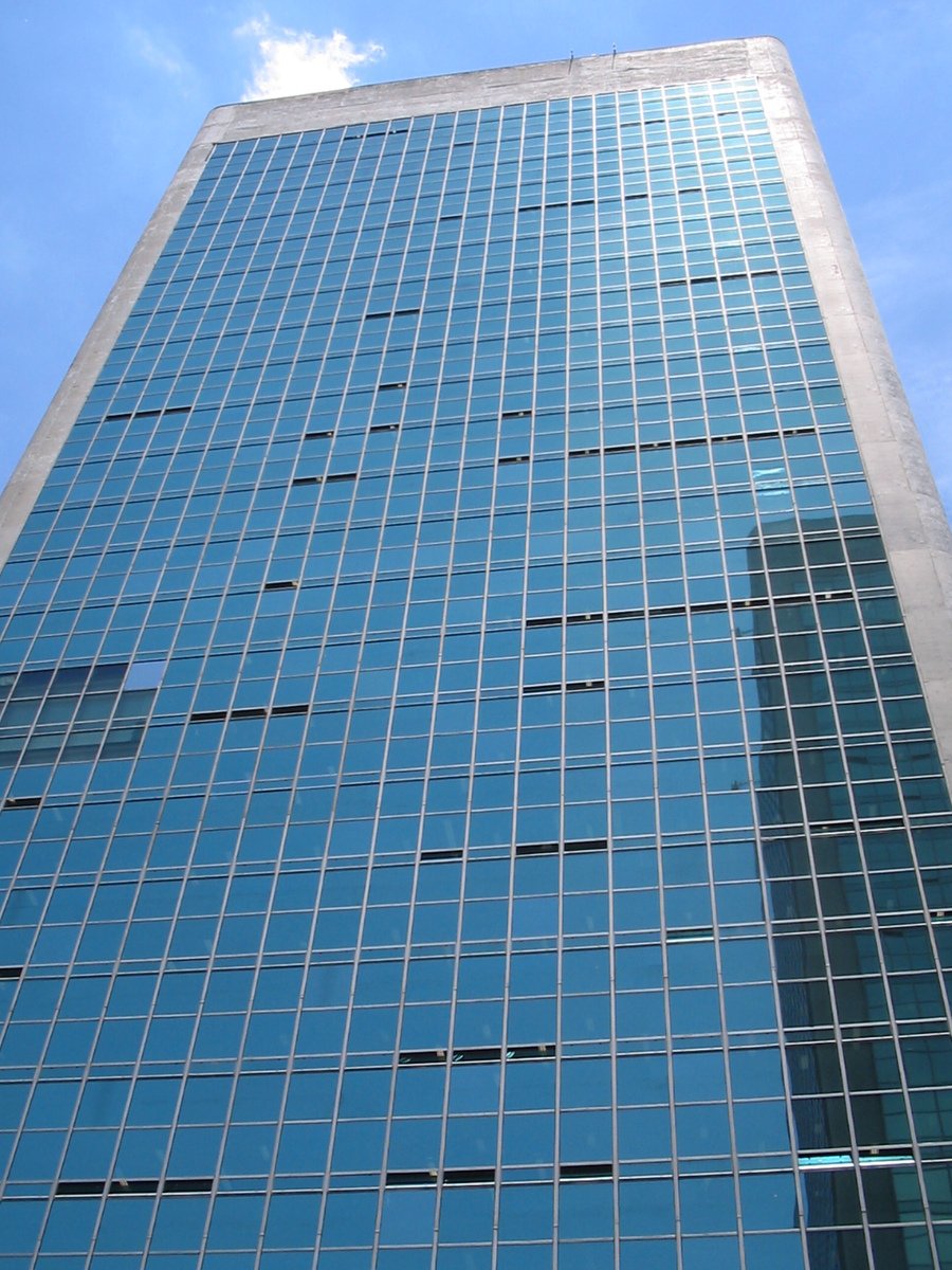 a tall glassy skyscr stands in front of a blue sky
