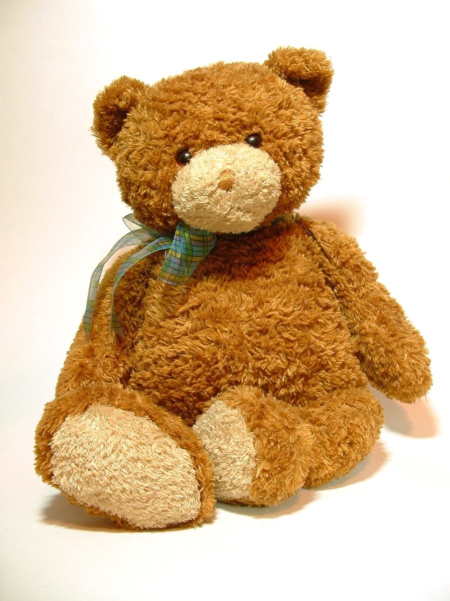 a teddy bear with a bow sitting on a white surface