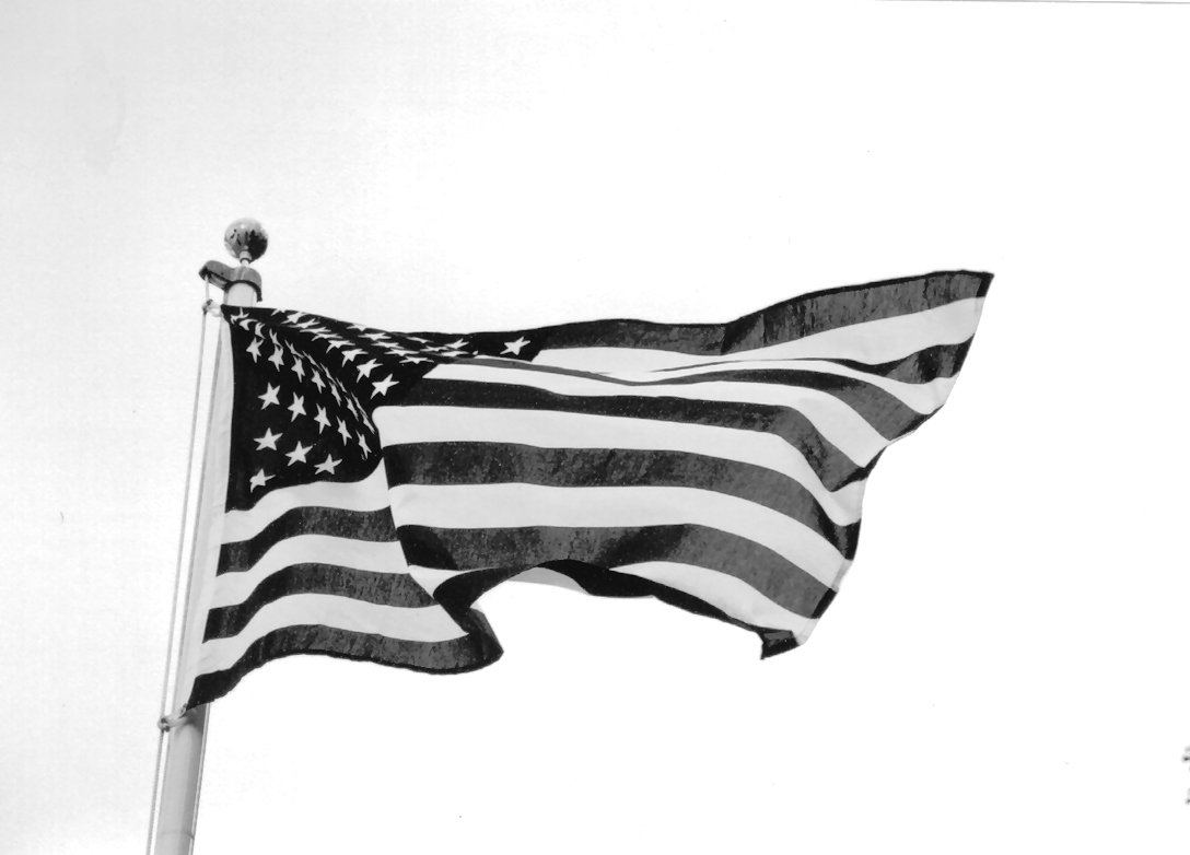 two american flags flying in the wind in black and white