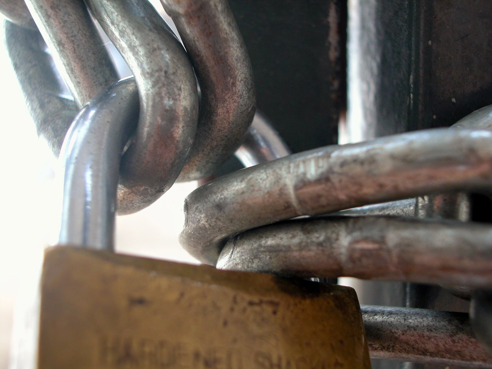 several rusty metal links are hung by the lock of a large steel object