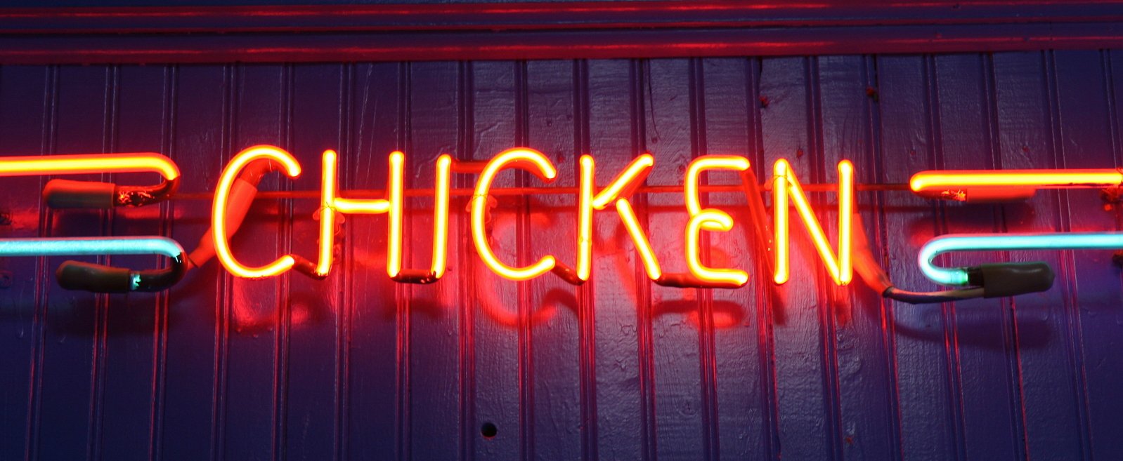 this neon sign says chicken street on the wall