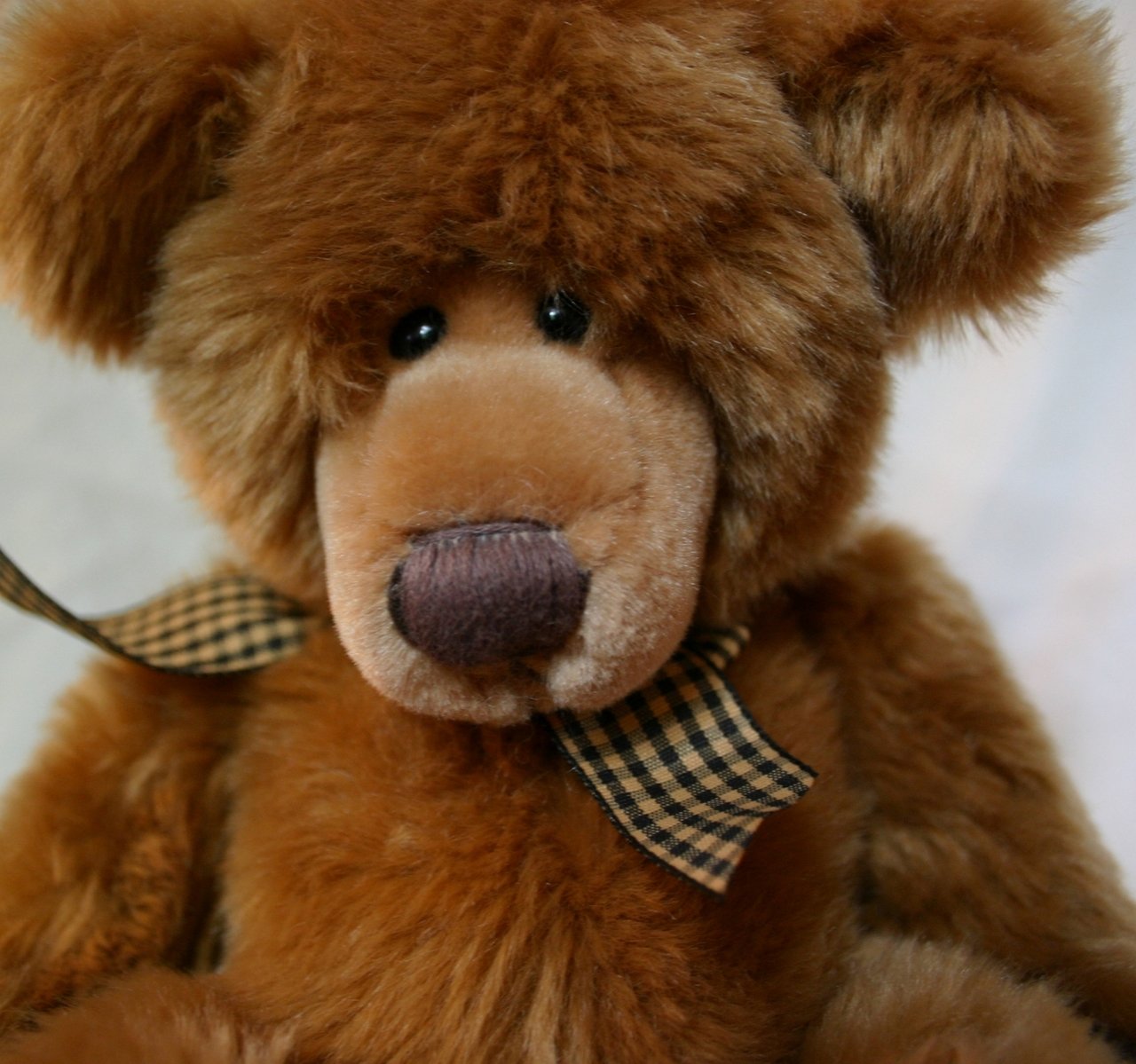 a brown teddy bear wearing a checkered bow tie